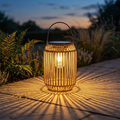 Bield rattan lantern glowing on a stone garden terrace at dusk