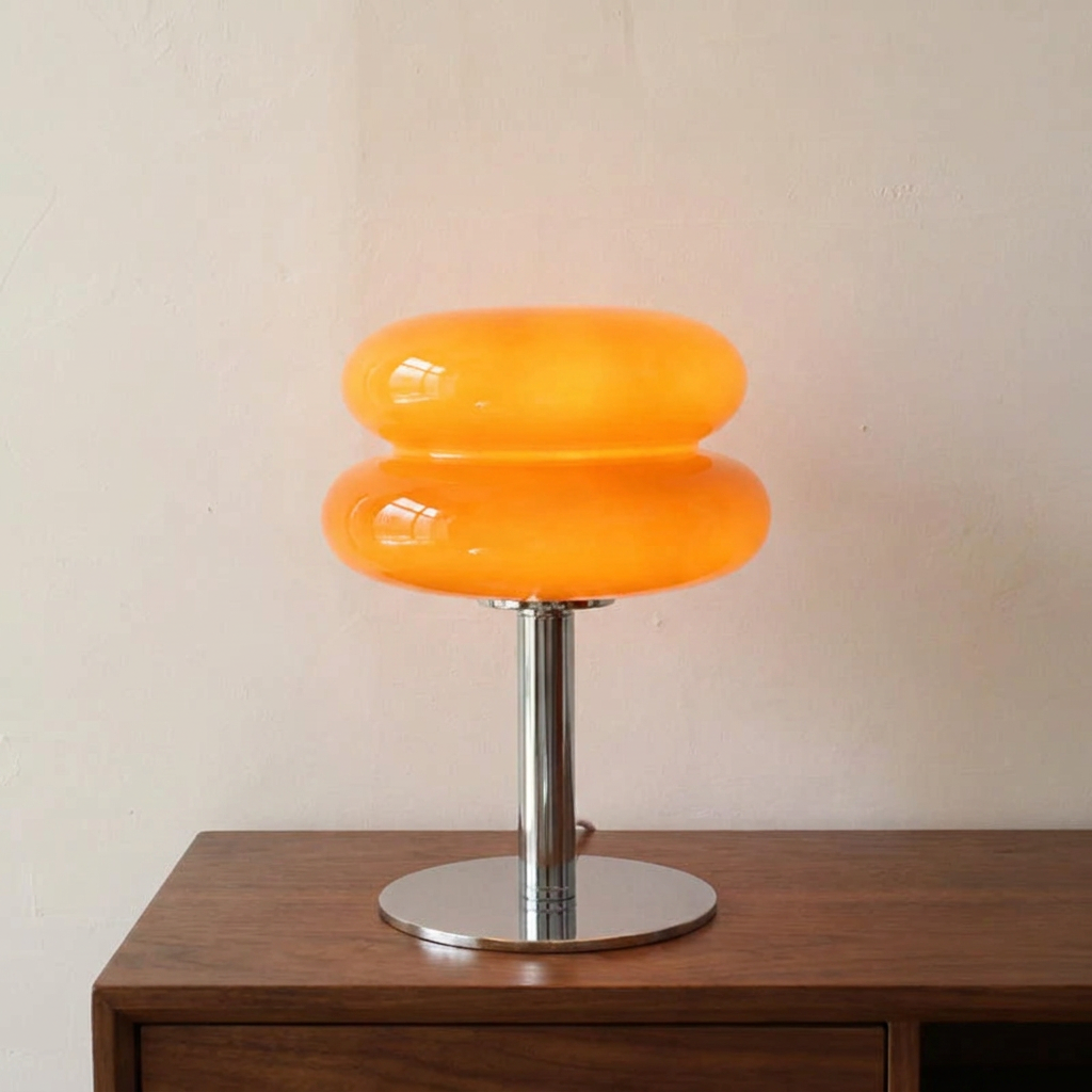 Marl glass table lamp lit on a walnut console against a plaster wall