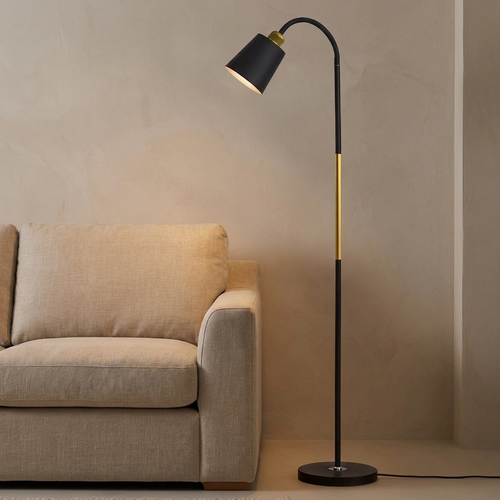 Furze iron floor lamp lit beside a linen sofa in a warm neutral living room