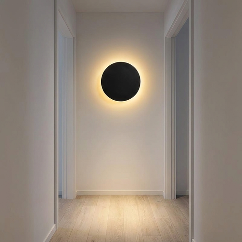 Amble wall light in a hallway at night above pale oak flooring