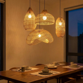 Rattan chandelier lit above a walnut dining table