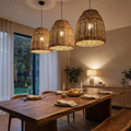 Rattan pendant light lit above a walnut dining table