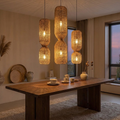 Rattan chandelier lit above a walnut dining table