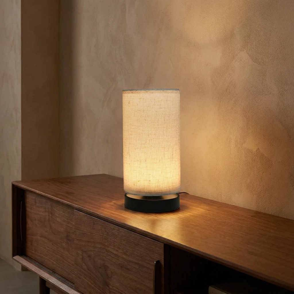 Scree table lamp lit on a walnut console against a plaster wall
